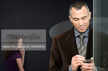 Woman with cellphone and man with handheld computer