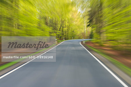 Driving along paved road through the spring forest at Amorbach in Odenwald, in Lower Franconia, Bavaria, Germany