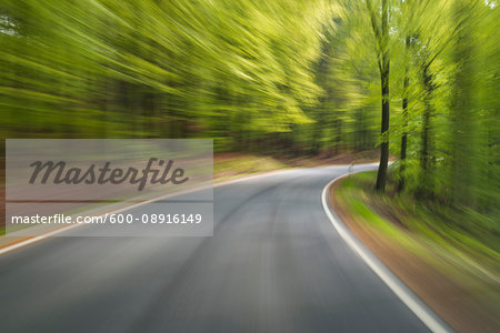 Driving along paved road through the spring forest at Amorbach in Odenwald, in Lower Franconia, Bavaria, Germany