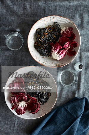 Overhead view of squid ink spaghetti dish and radicchio lettuce salad