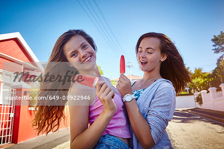 Portrait of two female friends, outdoors, holding ice lollies