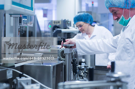 Workers operating machinery in pharmaceutical plant