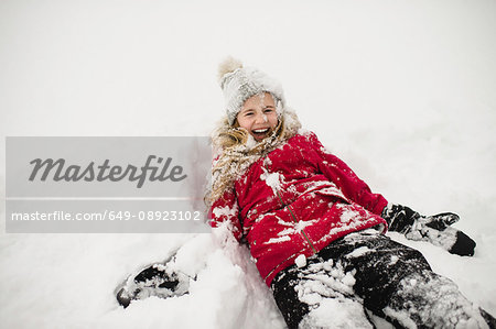 Smiling girl lying on back and covered in snow