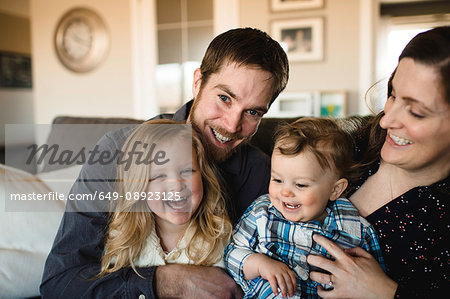 Portrait of mid adult parents with girl and baby boy on sofa together