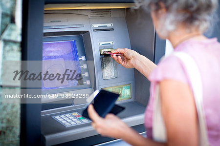 Mature woman inserting credit card into local french cash machine