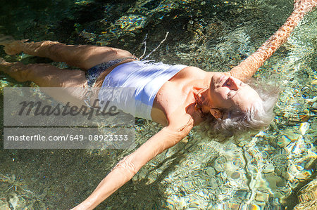 Woman wearing swimsuit arms open floating in water