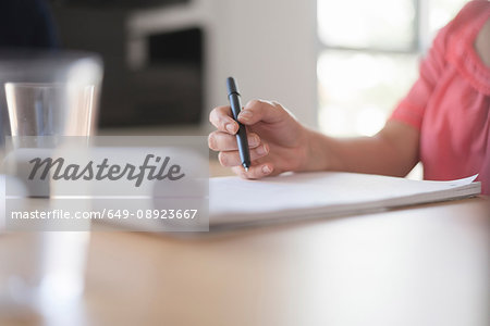 Woman writing notes on desk, close up of hand