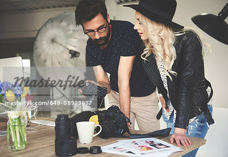 Photographer and stylist reviewing photographs on photography studio camera