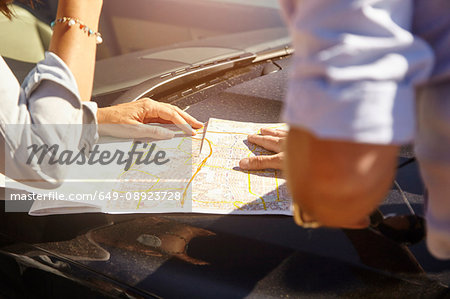 Couple looking at map on car bonnet, mid section