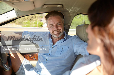 Couple in car, man in driver's seat, sitting facing woman