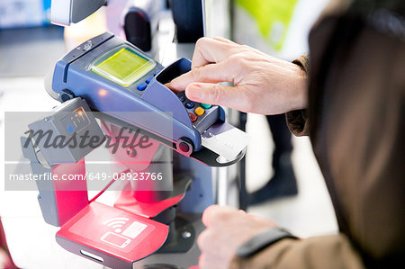 Mature woman using credit card machine to pay for shopping, close-up