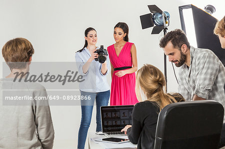 Fashion model and photographer reviewing shoot on digital SLR in photography studio