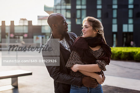 Young couple in city hugging and gazing at each other