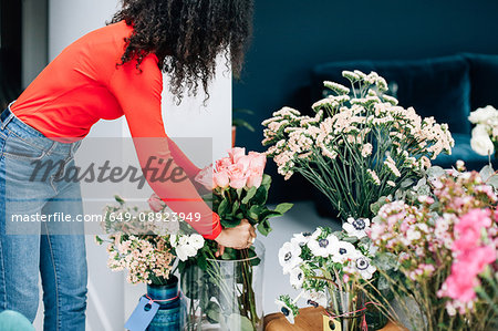 Female florist arranging roses in vase for shop display