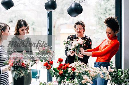 Florist and students arranging bouquets at flower arranging workshop