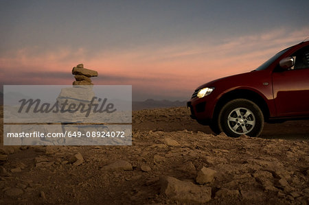 Car by stack of balanced rocks at sunset, San Pedro de Atacama, Chile