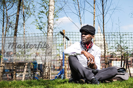 Businessman with scooter in park, London, UK