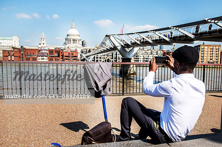 Businessman with scooter photographing St Paul's Cathedral, London, UK