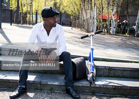 Businessman beside scooter on steps, London, UK