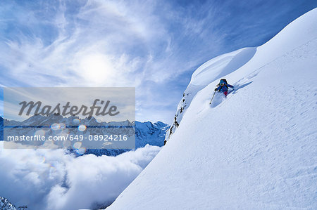 Woman skiing down steep mountainside in Swiss Alps, Gstaad, Switzerland