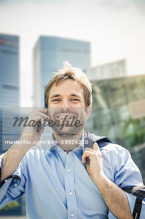 Portrait of happy businessman making smartphone call in city