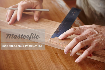 Hands of male carpenter using set square at workbench
