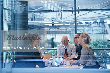 Window view of businesswomen and men having discussion in conference room