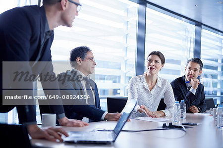 Businessman using laptop to make presentation to team