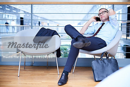Businessman sitting making smartphone call on office balcony