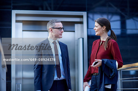 Businesswoman and man walking and talking on office balcony