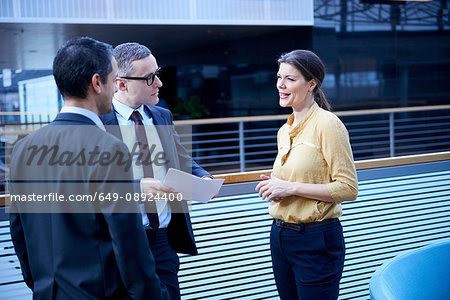 Businesswoman and men with paperwork in office atrium