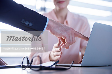 Cropped shot of businessman pointing at laptop on office desk