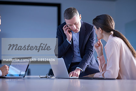 Business team making smartphone call and using laptop on office desk Business team making smartphone call and using laptop on office desk