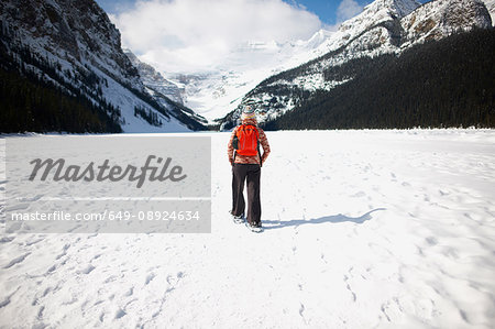 Hiker wearing snowshoes hiking on snow covered landscape, Lake Louise, Canada