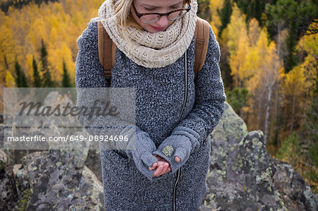 Young woman standing on mountain, holding rock in gloved hand, Sverdlovsk Oblast, Russia