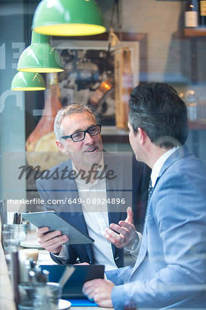 Two businessmen having discussion in restaurant window seat