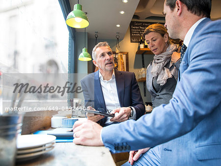 Businessmen and woman having discussion in restaurant window seat