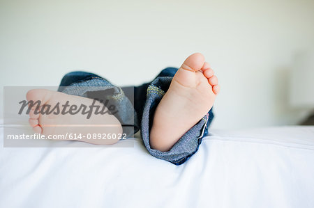 View of male toddler's bare feet, lying on bed