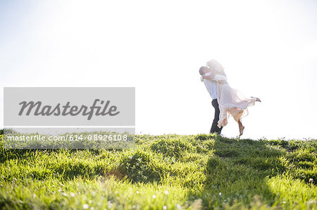 Romantic couple kissing on sunlit grassy hill