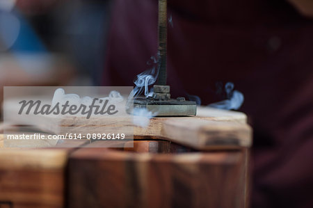 Close up of branding iron burning imprint onto chopping board in factory