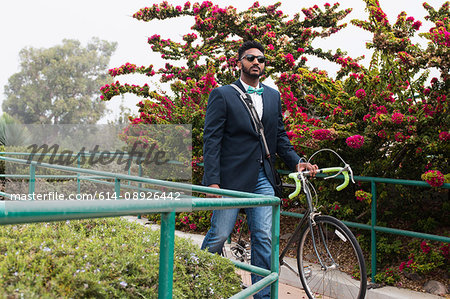 Young man pushing bicycle onto rail station platform