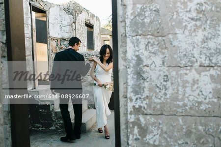 Bride and groom outdoors, holding hands, smiling