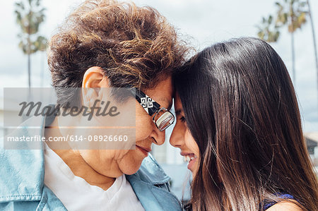 Portrait of grandmother and granddaughter head to head hugging