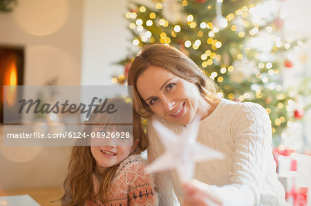 Portrait smiling mother and daughter holding Christmas star