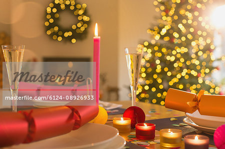 Candles, champagne and Christmas crackers on table