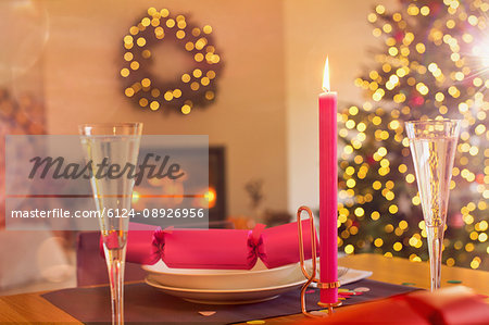 Champagne flute, candle and Christmas cracker on ambient table