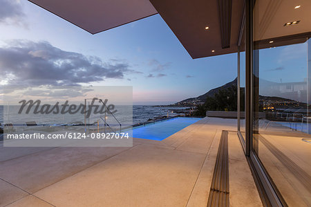Patio with lap swimming pool and ocean view at dusk
