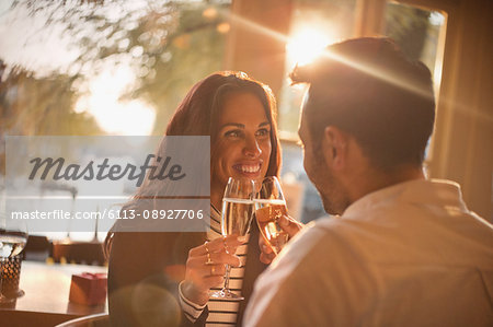 Affectionate young couple toasting champagne glasses in restaurant
