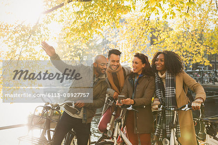 Friends with bicycles along sunny autumn canal