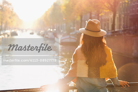 Woman looking at sunny autumn canal view, Amsterdam Woman looking at sunny autumn canal view, Amsterdam